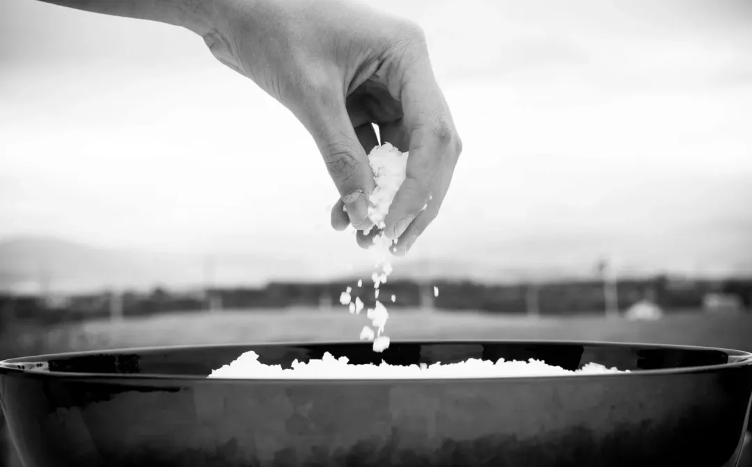 Man taking a handful of flake sea salt from a bowl